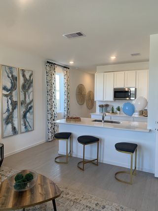 A sleek kitchen with a white island, modern barstools, and contemporary art accents illuminated by soft lighting.