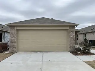 A charming brick home with a two-car garage and a fresh concrete driveway in Wildcat Ranch by Lennar (Crandall, TX).