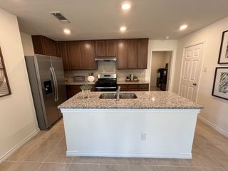 Model Home Rich brown cabinetry paired with stainless steel appliances. Center island offers extra prep space and seating options.
