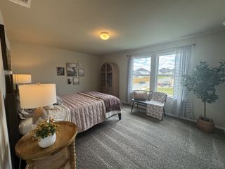 A cozy bedroom with soft carpeting, a large window, and stylish decor, creating a welcoming and serene atmosphere.