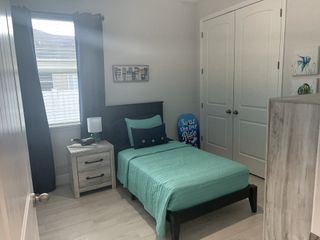 A cozy bedroom with teal bedding, light wood furniture, and coastal-themed decor.
