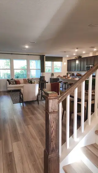 An open-concept living and dining space with rich wood tones, a spacious kitchen island, and modern pendant lighting.
