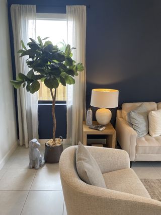 A cozy living room with a beige sofa, chic armchair, indoor plant, and elegant lighting.
