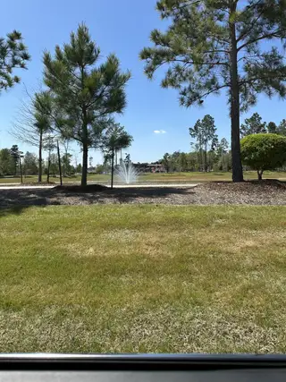 Lush greenery and a serene pond with a fountain in Evergreen by Chesmar Homes (Conroe, TX).