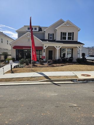 A charming brick home with a welcoming porch and manicured lawn in Auburn Glen by Taylor Morrison (Dacula, GA).