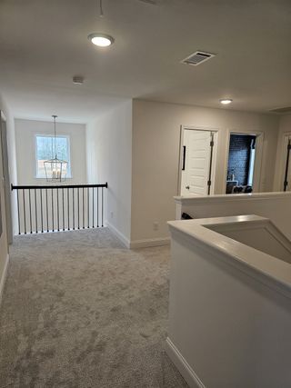 Model Home A cozy loft space with plush carpeting, natural light, and sleek black railing accents.