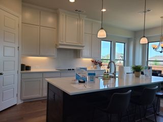 A modern kitchen featuring sleek white cabinets, a spacious island with a sink, and elegant pendant lighting.