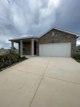 A modern brick home with a welcoming porch and garage in Hennersby Hollow by Starlight Homes (San Antonio, TX).