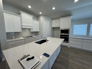 A sleek modern kitchen with white quartz countertops, a stylish herringbone backsplash, and an open-concept layout.