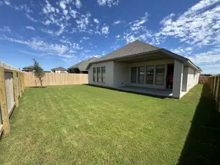 A stunning backyard with a covered patio, green lawn, and privacy fencing in Kallison Ranch by Perry Homes (San Antonio, TX).