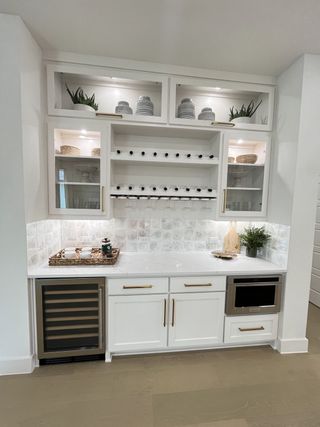 A chic wet bar with glass cabinets, wine storage, and a built-in beverage cooler, offering modern convenience and style.