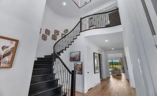 Model Home A grand foyer with a sweeping staircase, modern art, and elegant wood flooring.