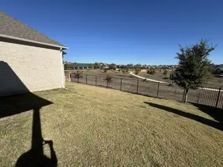 Spacious backyard with lush grass and a scenic view in Sunfield by CastleRock Communities (Buda, TX).