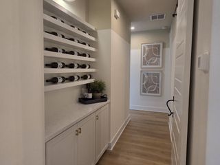 A modern hallway with a built-in wine rack, sleek cabinets, and elegant decor on wood flooring.
