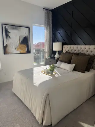 A chic bedroom featuring a tufted bed, geometric accent wall, and large artwork.