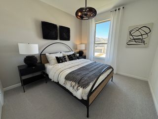 A chic guest bedroom with black accents, a rattan bed frame, and artistic wall decor.