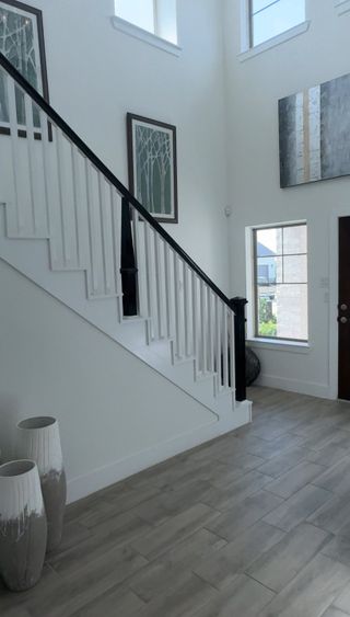 Model Home A bright entryway with elegant stairs, tasteful artwork, and polished wooden floors.