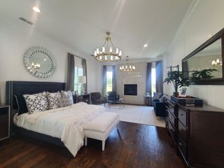 Model Home Elegant bedroom with a plush bed, chandeliers, stylish decor, and a cozy fireplace, creating a serene retreat.