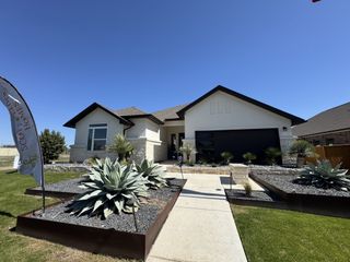 A modern home with sleek landscaping and a neutral facade in Foxbrook by Scott Felder Homes (Cibolo, TX).