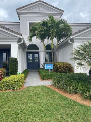 A beautiful white home with palm trees and a manicured lawn in Westlake by Minto Communities (Westlake, FL).