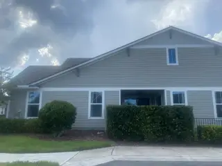 Street view A charming gray-paneled home with manicured hedges in West End At Town Center In Nocatee by Dostie Homes (Ponte Vedra Beach, FL).