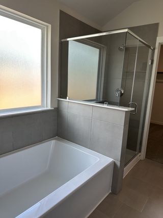A modern bathroom featuring a sleek glass shower and a spacious bathtub with frosted windows for privacy.