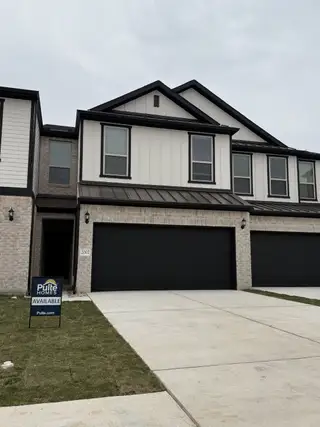 Street view A modern duplex townhome with black-framed windows, a spacious driveway, and elegant exterior finishes in Whitestone Preserve by Pulte Homes (Cedar Park, TX).