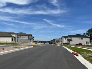 Newly constructed homes line a spacious street in Pearl Estates by Lennar, Lutz, FL, under a clear blue sky.