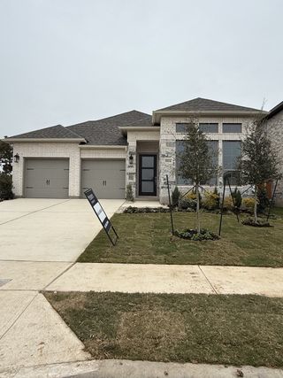 A modern brick home with a sleek entrance and manicured lawn at Parkside Peninsula 50' by Perry Homes (Georgetown, TX).