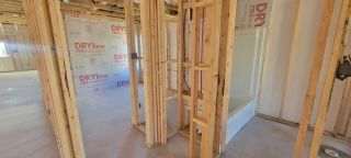 An in-progress construction site showing framed walls, plumbing, and a bathtub installation.