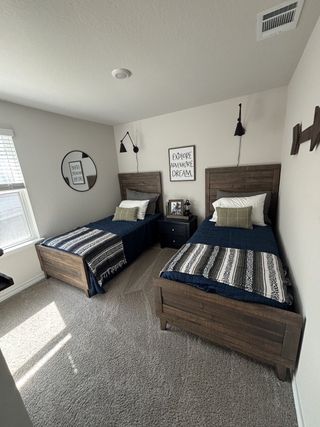 A cozy bedroom features twin rustic wooden beds, stylish linens, and modern wall sconces.