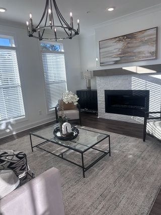 A chic living room with elegant chandelier lighting, a modern fireplace, and stylish decor.