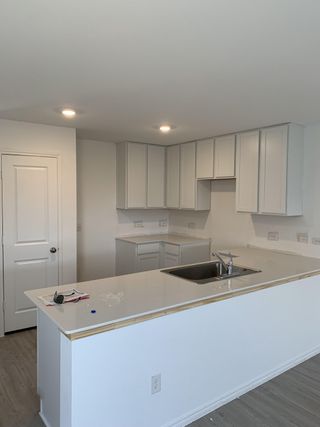 A modern kitchen featuring sleek white cabinetry, a spacious island with a sink, and recessed lighting.