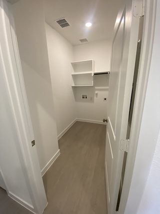 A sleek utility room with white walls, built-in shelving, and recessed lighting for a clean, organized laundry space.