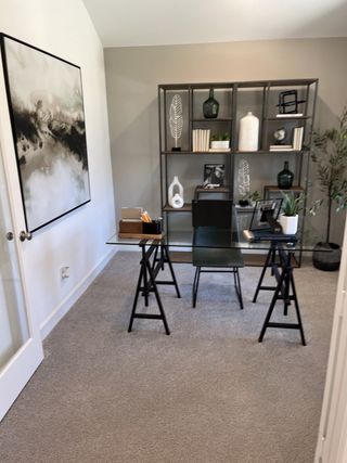 A stylish home office featuring a glass desk, industrial-style shelving, and soft neutral tones for a calming workspace.