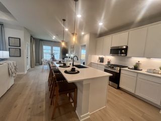 A sleek kitchen with a spacious island, pendant lighting, modern appliances, and light wood floors. Perfect for entertaining guests.