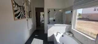 Modern bathroom featuring a walk-in shower, sleek marble tiles, and large windows for natural light.