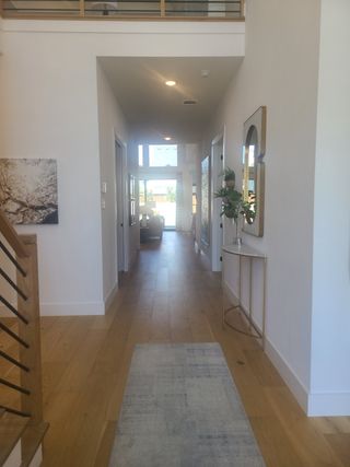 A bright hallway with modern decor, wood flooring, and ample natural light, creating an inviting and spacious feel.