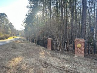 A picturesque road lined with trees and a classic brick fence welcomes you to Watkins Glen by Exeter Building Company in Wake Forest, NC.