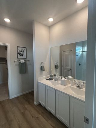 A contemporary bathroom featuring dual sinks, elegant fittings, and warm wood flooring.