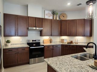 A modern kitchen featuring sleek dark wood cabinets, granite countertops, and stainless steel appliances.