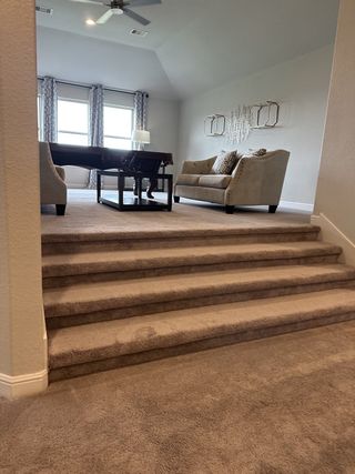 A cozy living area with plush carpeting, elegant sofas, and large windows allowing natural light to fill the space.