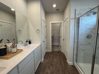 A sleek bathroom with a modern vanity, large mirror, and spacious shower featuring elegant marble tiles.