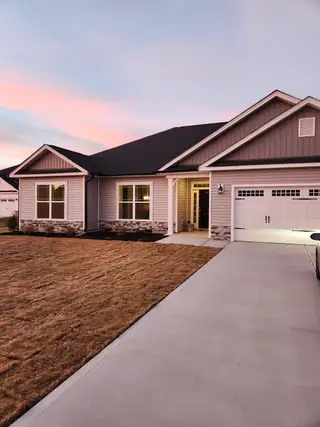 A charming modern home with a spacious driveway and manicured yard in Cool Water by Adams Homes (Bailey, NC).