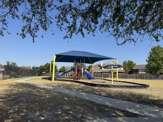 A vibrant playground with blue and yellow shade structures, perfect for family fun in Blackhawk by GFO Home (Pflugerville, TX).