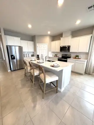 A modern kitchen with sleek white cabinets, stainless steel appliances, and an island featuring stylish bar seating.