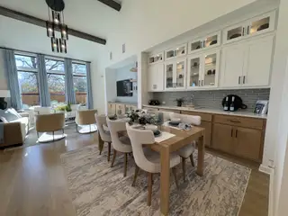 A bright, open-concept dining and living area with elegant cabinetry, modern furniture, and floor-to-ceiling windows.