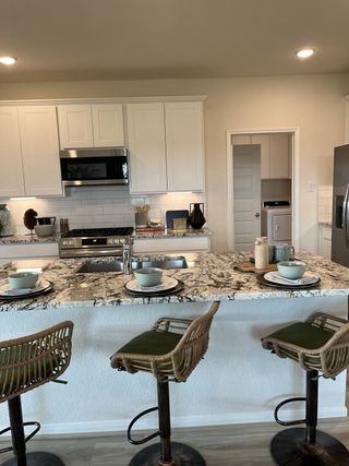 A modern kitchen with white cabinets, granite countertops, and elegant barstools, perfect for casual dining and entertaining.