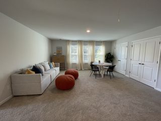 A cozy living space with a plush sofa, bright windows, and a chic dining nook, enhanced by stylish decor and soft lighting.