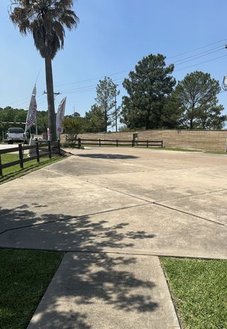 A scenic entrance with flags and trees at Walden on Lake Conroe by Legend Homes (Montgomery, TX).